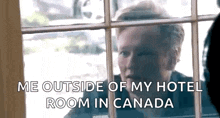 a man is standing in front of a window and talking to another man .