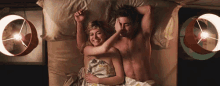 a man and a woman are laying in bed with their arms up