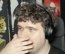 a man is wearing headphones and covering his nose with his hand