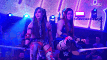 two women in a wrestling ring with a wwe logo in the corner