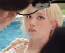 a woman with blonde hair is looking at the camera while a man takes a picture of her .