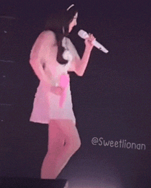 a woman in a white dress is holding a microphone and a fan .