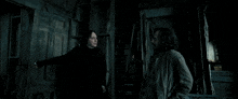 two men are standing in a dark room and one is pointing a wand at the other