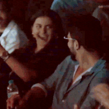 a man and a woman are sitting in a dark room laughing