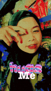a woman wearing a hijab is taking a selfie with the words " hugs me " behind her