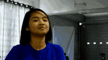 a woman in a blue shirt is smiling and looking up