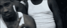 a man in a white tank top has a tattoo on his chest