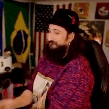 a man with a beard is wearing a hat and a sweater with a floral pattern