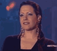a woman wearing a black shirt and earrings is smiling in a video from italia
