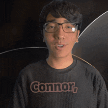 a young man wearing glasses and a black shirt with the word connor on it