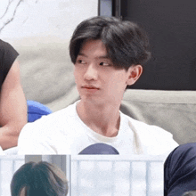 a young man sitting on a couch with a white shirt on