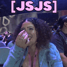 a woman in a denim jacket laughs in front of a sign that says [ usjs ]