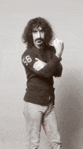 a man with curly hair and a mustache is wearing a black sweater with the number 56 on the sleeve