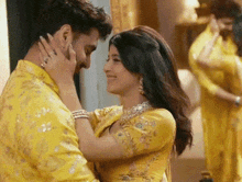 a man and a woman in yellow clothes are kissing .