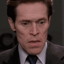 a close up of a man 's face with a suit and tie