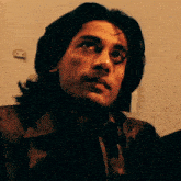 a close up of a man 's face with a wall in the background