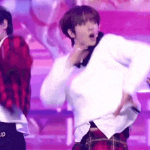 a man in a plaid skirt is dancing on a stage .