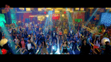 a large group of people are dancing in a room with a sign that says ' bollywood ' on it