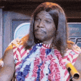 a man with long hair is wearing a red , white and blue shirt and a lei .