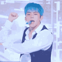 a young man with blue hair is wearing a white shirt and a black vest .