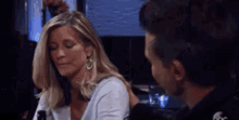 a man and a woman are sitting at a table and talking to each other . the woman is wearing earrings .