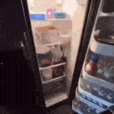 an open refrigerator with bottles of water on the shelf