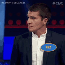 a man in a suit has a name tag that says kuz on it