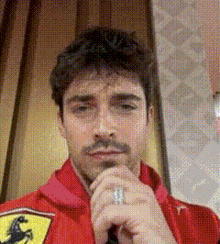 a man wearing a red jacket with a ferrari logo on it is taking a selfie .