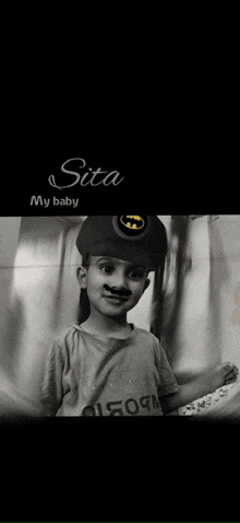 a black and white photo of a little boy wearing a batman hat .