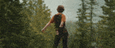 a man is standing in the middle of a forest .