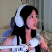 a woman wearing headphones is sitting in front of a microphone in a room .