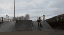 a person is riding a scooter down a ramp at a skate park