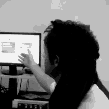 a woman is sitting in front of a computer and pointing at it