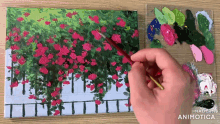 a person is painting a picture of pink flowers on a canvas .