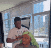 a man is applying makeup to a woman 's face in front of a large window