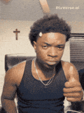 a man is giving a thumbs up in front of a cross on the wall