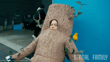 a person dressed as a tree trunk with a yellow bird on it