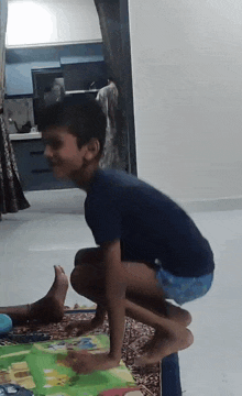 a young boy is squatting on a rug in a room