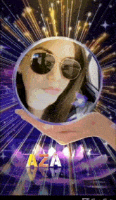 a woman in sunglasses is holding a sphere with the aza logo in the background