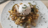 a white plate topped with a poached egg and vegetables .
