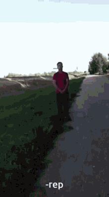 a man in a red shirt is standing on the side of a road with a cigarette in his mouth