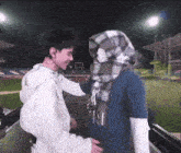 a man with a scarf around his head talks to another man with a scarf around his head