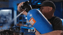 a man is holding a large blue container that says rtj