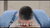 a man is laying on a bed with a cherry pie in his mouth and says `` cherry pie time '' .