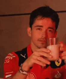 a man in a ferrari shirt is drinking a glass of milk