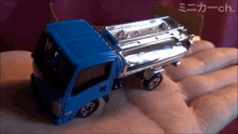 a blue toy truck is being held in someone 's hand ..