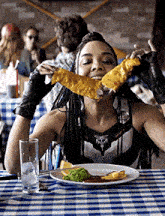 a woman is sitting at a table eating a huge piece of food