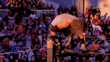 a wrestler is kneeling down in front of a crowd while wearing a t-shirt that says triple h on it