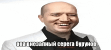 a bald man in a white suit and black shirt is smiling in a meme