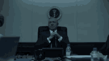 a man in a suit and tie sits at a table with a bottle of aquafina water in front of him
